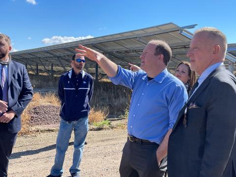 Governor Polis and others standing in front of solar panels.